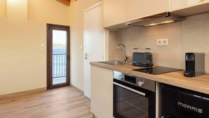 A modern kitchen with a wooden countertop, stainless steel appliances, and a view through a glass door. - Studio Tepes - Velis Samos Sea View Balcony Suite (Kokkari)