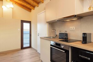 Eine moderne Küche mit Holzausziehtisch, Edelstahlgeräten und Blick durch eine Glastür.