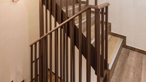 A wooden staircase with a handrail and a light fixture on the wall. - Studio Tepes - Velis Samos Sea View Balcony Suite (Kokkari)