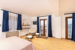 A modern bedroom with a bed, a chair, a TV, and a balcony with a view. - Studio Tepes - Natassa Samos SeaView Balcony Suite (Kokkari)