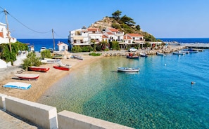 A coastal town with clear blue waters, boats on the shore, and buildings with red-tiled roofs. - Studio Tepes - Natassa Samos SeaView Balcony Suite (Kokkari)