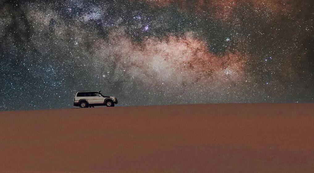 Un véhicule sur une dune, avec un ciel étoilé en arrière-plan.