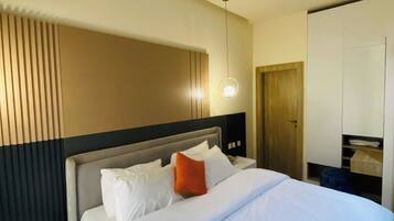 A hotel room with a bed, bedside tables, a wardrobe, and a bathroom.