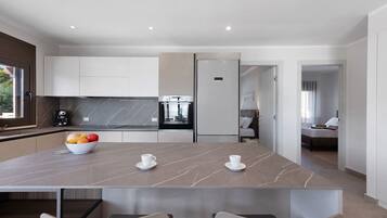 Una cucina moderna con un piano di lavoro in marmo, una ciotola di frutta e una tazza di caffè.