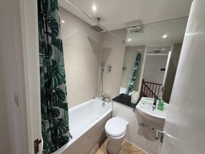 A modern bathroom with a bathtub, toilet, and sink. - 2BDR House with Private Garden and Parking (Greater London)