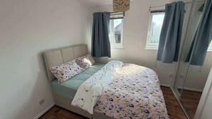 Ein Schlafzimmer mit Bett, Fenster und Tür.