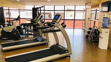 Ein Fitnessstudio mit Laufbändern, Kraftgeräten und einem Wasserspender.