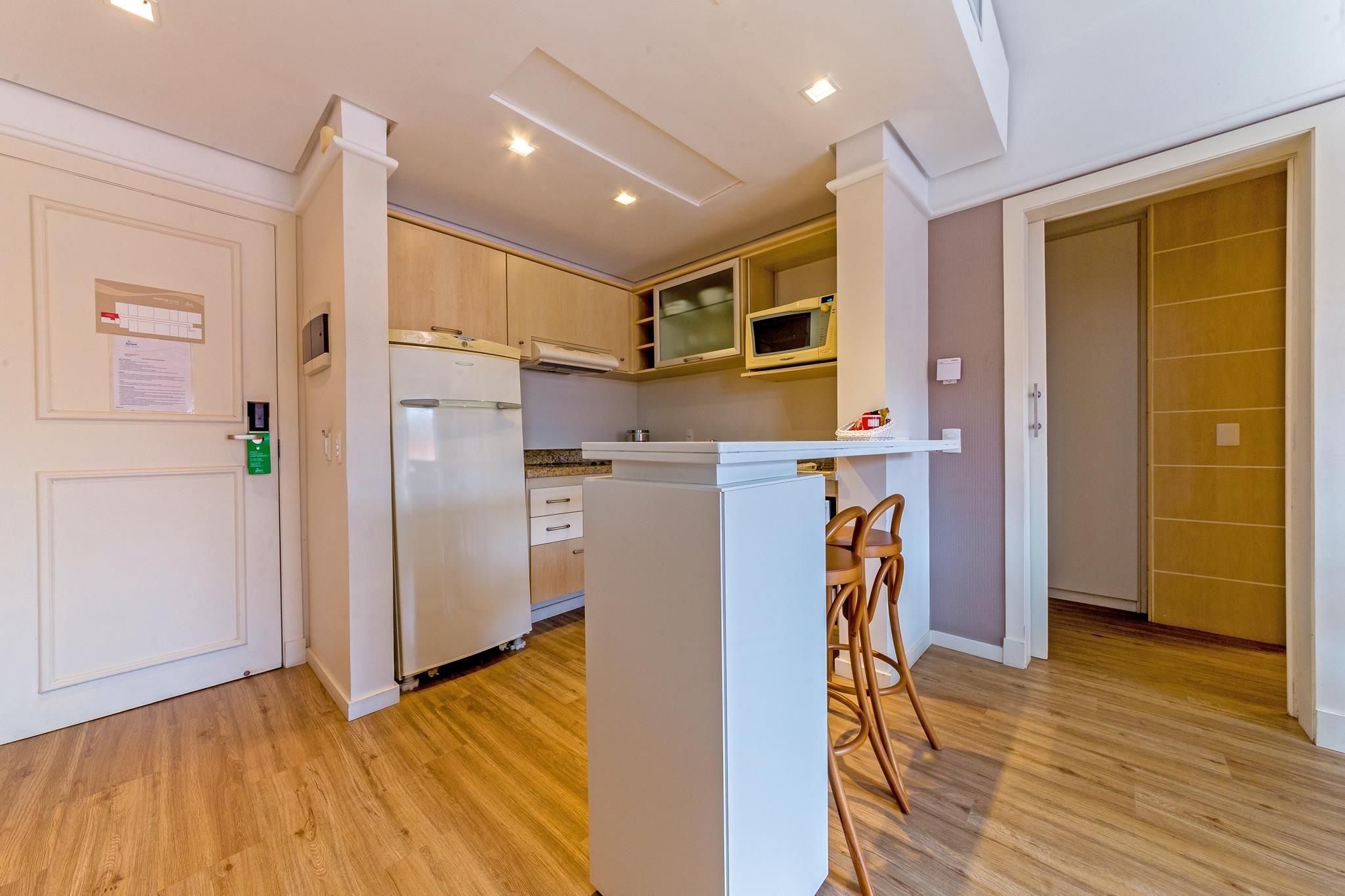 A compact kitchen with a refrigerator, microwave, and wooden cabinets.
