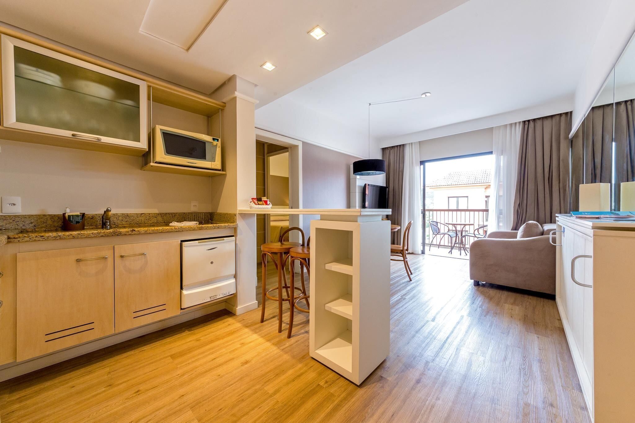 Eine moderne Küche mit Holzausstattung, einer Mikrowelle und einem Essbereich mit einer Couch und Stühlen.