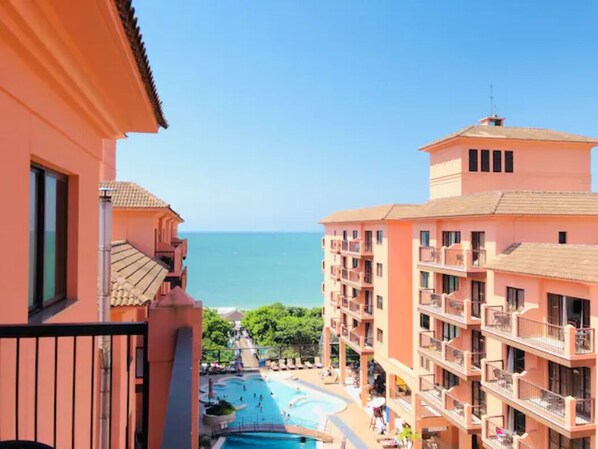 Un hotel con piscina, balcones y vistas al mar.