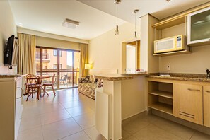 A hotel room with a kitchen area, a dining table with chairs, a sofa, and a balcony with a view. - Suite w/ Sea/pool View Luxury Resort Jurere Jbv142 (Florianópolis)