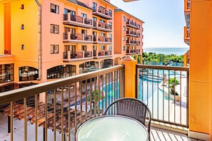 Ein Balkon mit Blick auf einen Swimmingpool und ein mehrstöckiges Gebäude mit Balkonen.