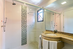 A modern bathroom with a glass-enclosed shower, a granite countertop sink, and a large mirror. - Suite w/ Sea/pool View Luxury Resort Jurere Jbv142 (Florianópolis)