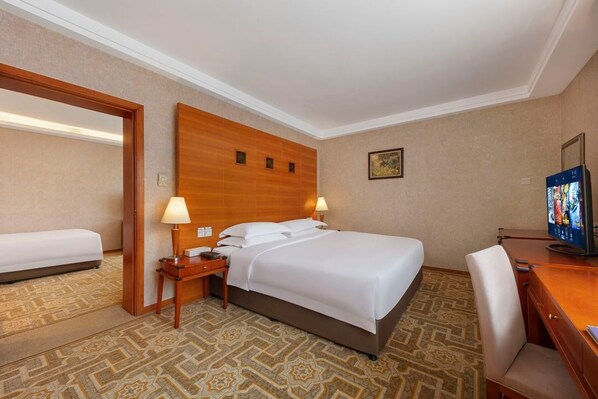Una habitación de hotel con una cama grande, un escritorio con silla, un televisor y un espejo.