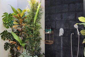 Een badkamer met een zwarte wand, een douche en een plank met toiletartikelen.