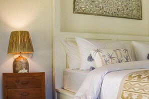 Een slaapkamer met een bed, kussens, een nachtkastje en een decoratief object aan de muur.