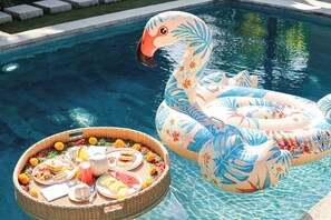 Una piscina amb un flotsam de flamenc i una cistella de vimet plena d'aliments i begudes.