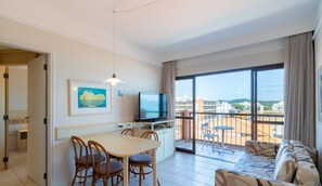 A hotel room with a dining area, a TV, a balcony with a view of the city, and a sofa. - Beachfront Resort Suite w/ Pool Jbv227 (Florianópolis)