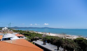 A coastal view with a beach, ocean, and distant mountains. - Beachfront Resort Suite w/ Pool Jbv227 (Florianópolis)