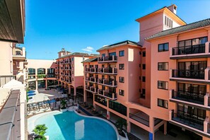 Ein mehrstöckiges Hotel mit Schwimmbad, Sitzgelegenheiten im Freien und Balkonen.