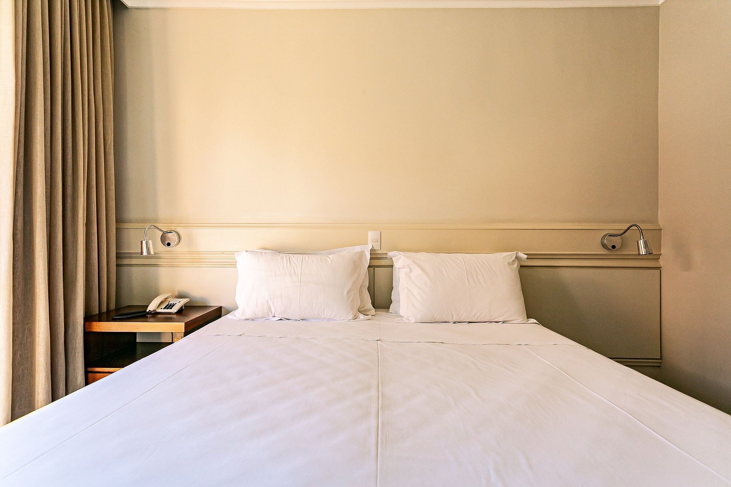 Una cama bien tendida con sábanas blancas en una habitación de hotel.
