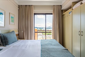 Une chambre d’hôtel avec un lit, une armoire et une fenêtre donnant sur un paysage urbain.
