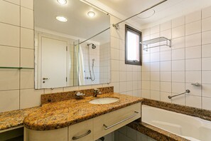 Ein Badezimmer mit Granitwaschtisch, Spiegel, Dusche und Badewanne.