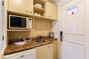 Une petite cuisine équipée comprenant un four à micro-ondes, un évier et des placards de rangement.