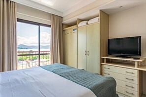 Une chambre d’hôtel avec un lit, un téléviseur posé sur un meuble, une armoire et un balcon offrant une vue sur les montagnes.