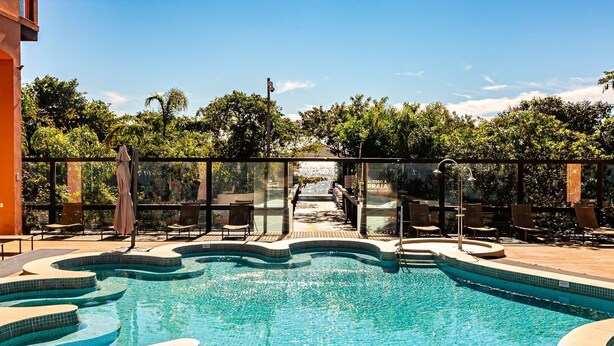 Ein Pool mit Glasbarriere, Liegestühlen und Blick auf eine natürliche Landschaft.
