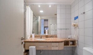 Ein Badezimmer mit Marmorwaschtisch, Spiegel, Handtuchhalter, Fön und Toilette.