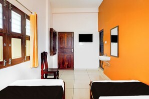 Habitación de hotel con dos camas, una puerta de madera, un televisor y un lavabo.