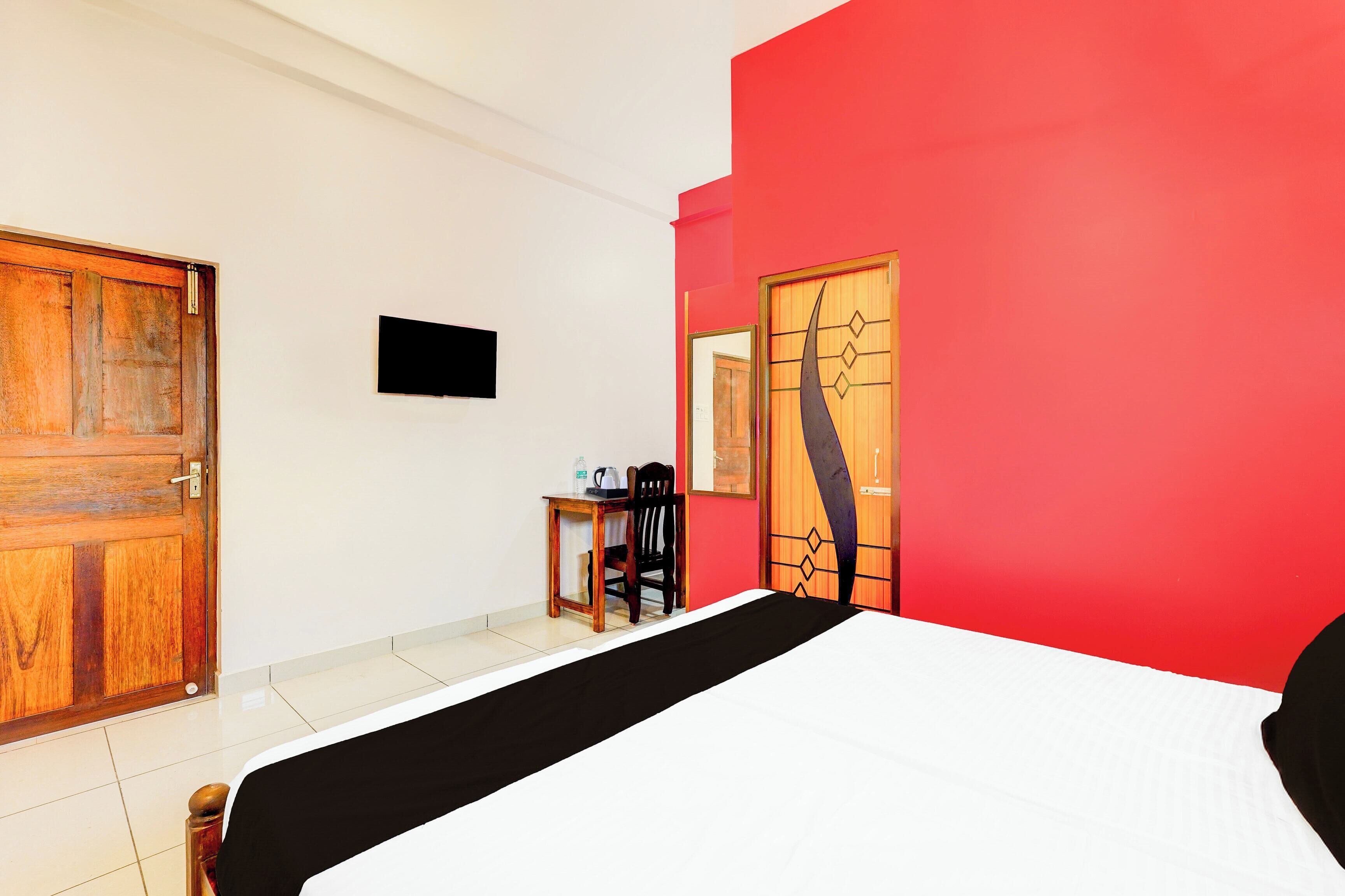 Una habitación de hotel con cama, escritorio, silla, televisor y puerta.