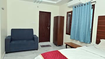 A bedroom with a bed, a sofa, a wardrobe, and a window with curtains.