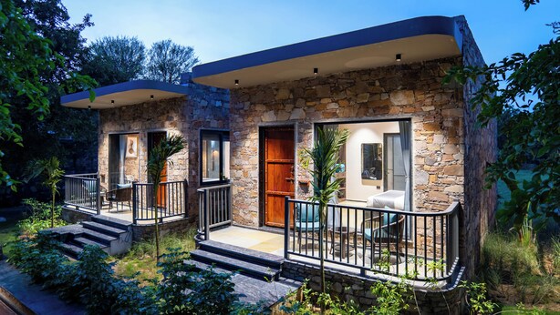 A two-story stone house with a balcony and a patio area.