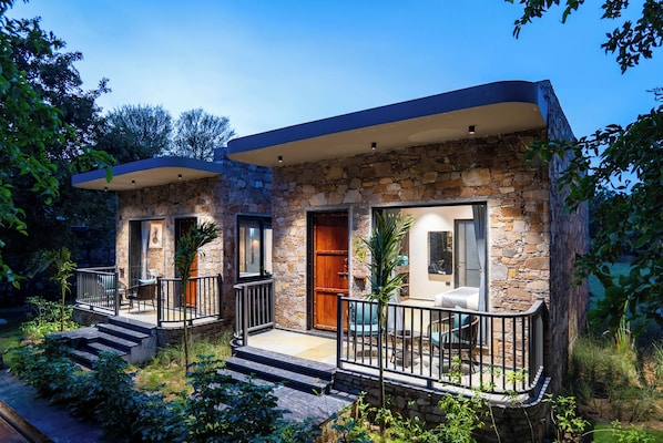 A two-story stone house with a balcony and a patio area.