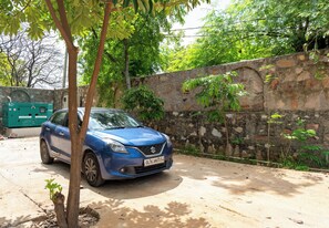 Un coche azul estacionado frente a un muro de piedra con follaje.