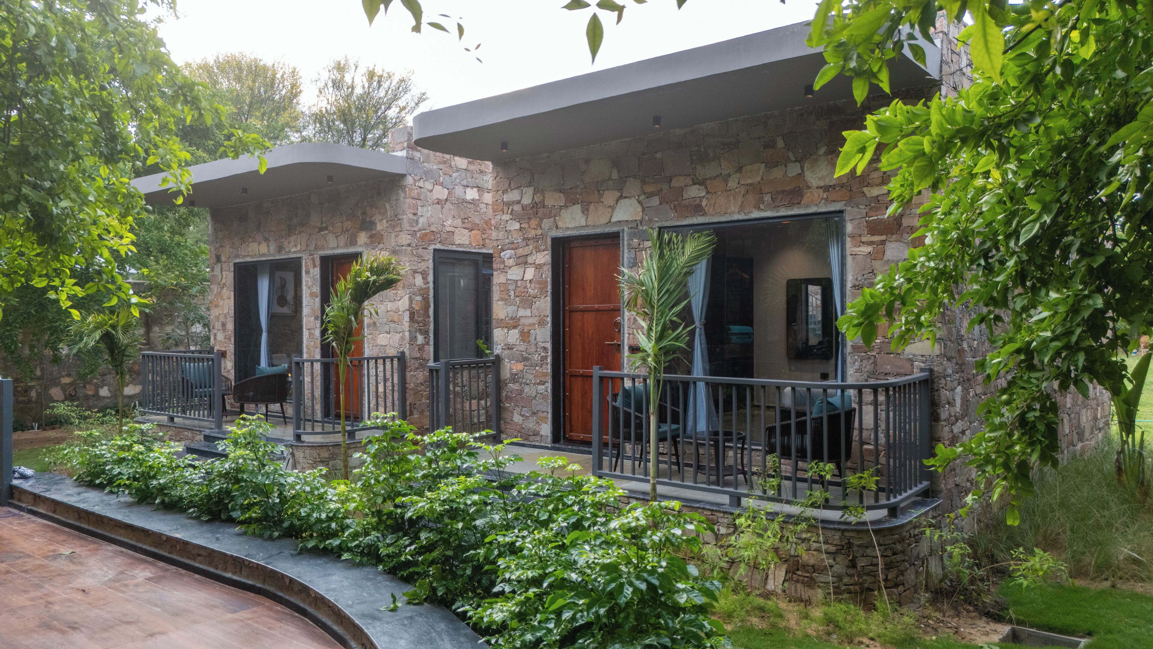 A stone building with balconies, a wooden door, and a small garden area.