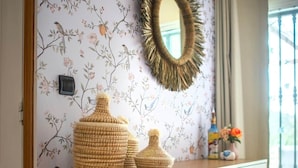 A wooden cabinet with woven baskets, a mirror, and a floral wallpaper. - Casa Carla Andalucia, Cabra, El Torcal (Almogía)