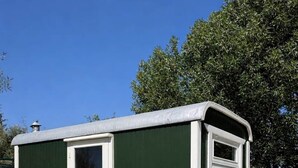 Una casa móvil pequeña, de un solo nivel, en tonos verde y blanco, con una puerta principal y una ventana.