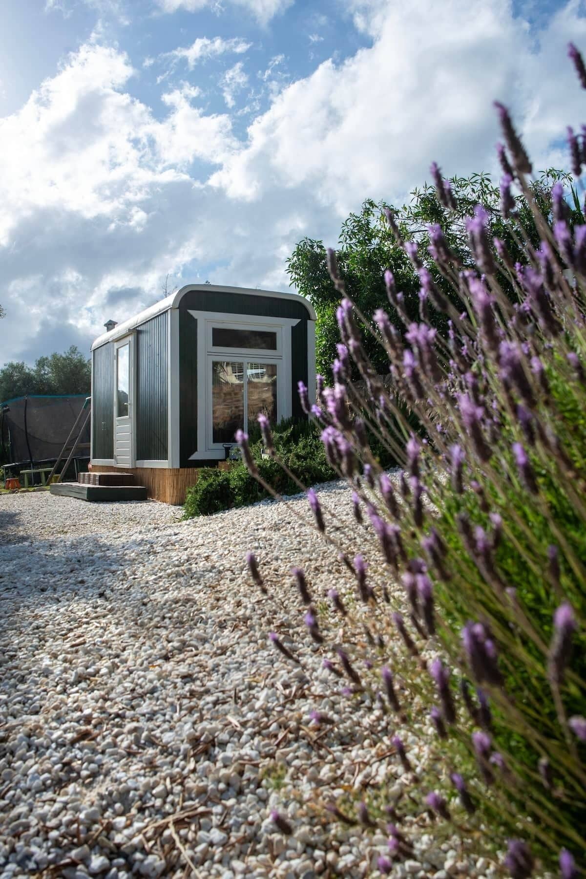 A modern, single-story building with a flat roof, a small porch, and a gravel driveway.
