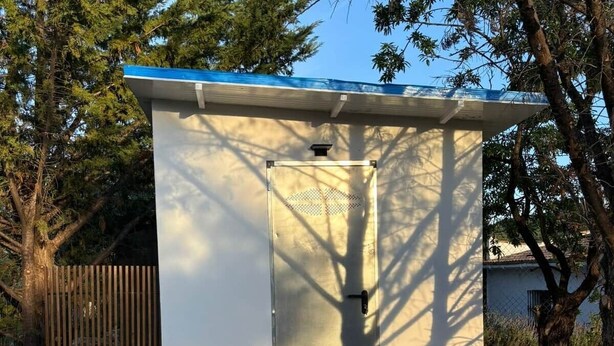 Una construcción pequeña de una sola habitación, con puerta, ventana y techo azul.