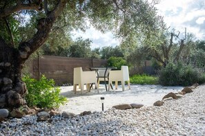 An outdoor seating area with a table and chairs, surrounded by pebbles and a wooden fence.