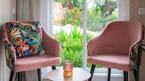 Una habitación con dos sillas, una mesita y un ventanal con vistas a zonas verdes.