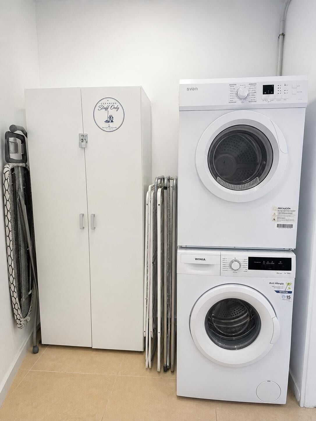 A laundry room with a white washing machine, a dryer, and a cabinet with a 'Stain Only' sign.