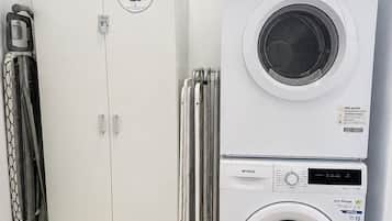 A laundry room with a white washing machine, a dryer, and a cabinet with a 'Stain Only' sign.