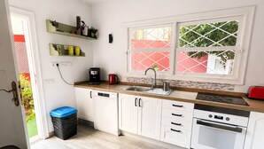 A modern kitchen with white cabinets, a wooden countertop, a built-in oven, a sink, and a window with a view of greenery.