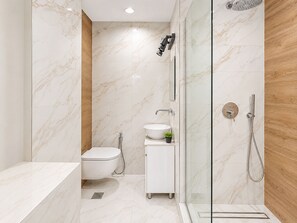 Ein modernes Badezimmer mit Toilette, Waschbecken und Dusche.