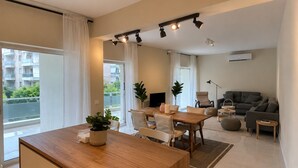 A modern apartment with a dining area, a sofa, a TV, and a balcony. - Solea by Neuvel (Glyfada)