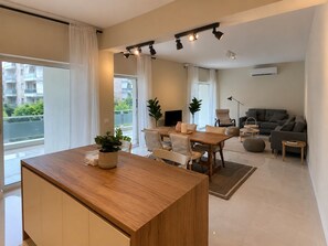 Eine moderne Wohnung mit Essbereich, einer Couch, einem Fernseher und einem Balkon.
